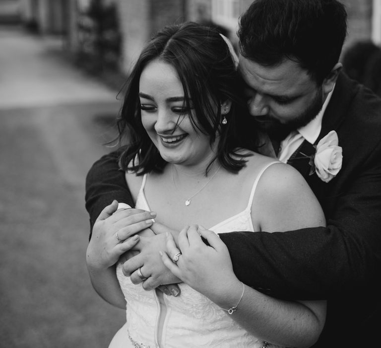 Groom hugging laughing bride in garden