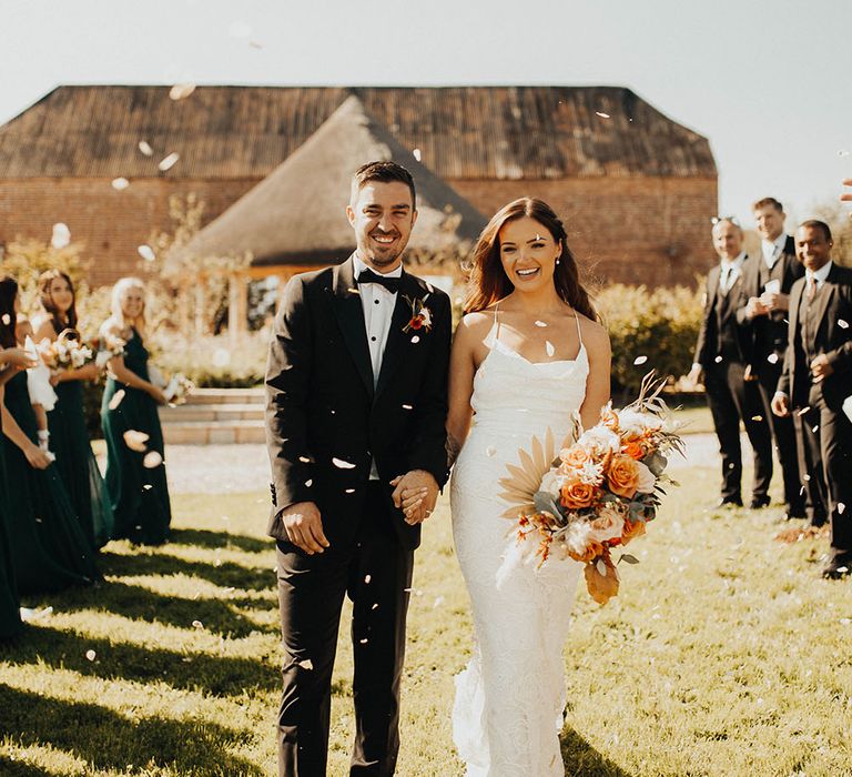 Bride and groom walk under confetti