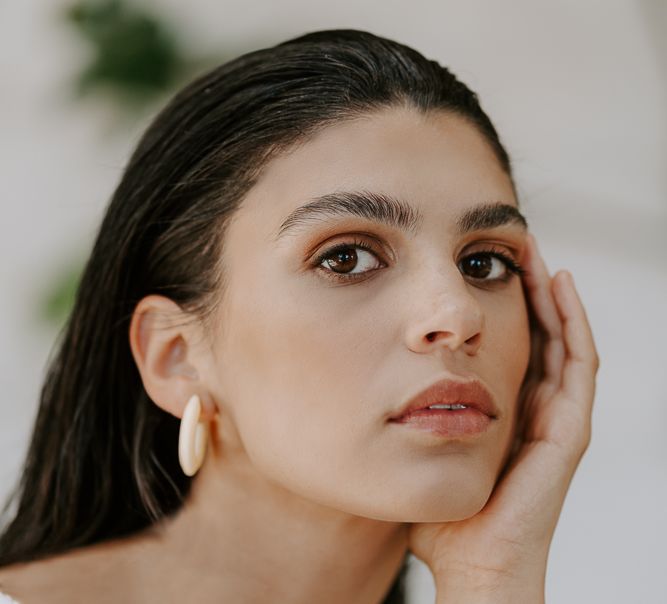 Wedding hair and makeup up with brown eyeshadow, light lipstick and slick back hair