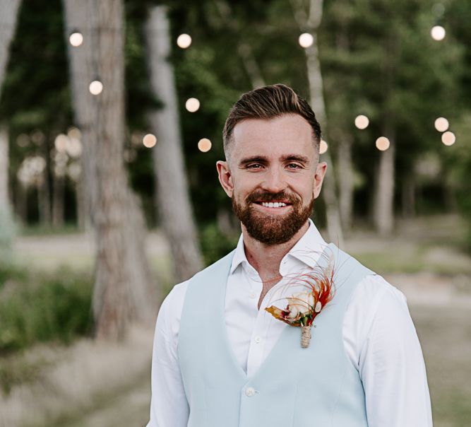 Groom wears pastel blue waistcoat and eye-catching buttonhole