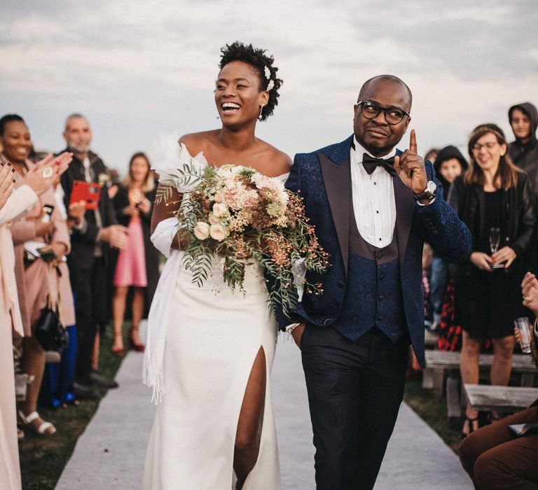 Father of the bride in a navy tuxedo escorting his daughter down the aisle 