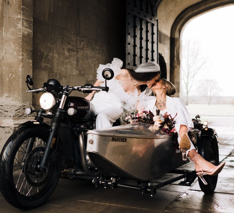 Two brides kissing in a motorbike and wedding sidecar at an inspiration shoot at Ashridge House in Hertfordshire 