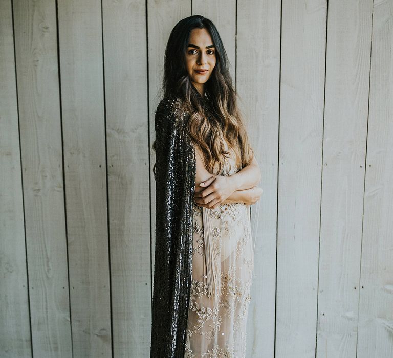 Stylish bride in a sheer wedding dress with black and gold embroidery in a sequin cape 