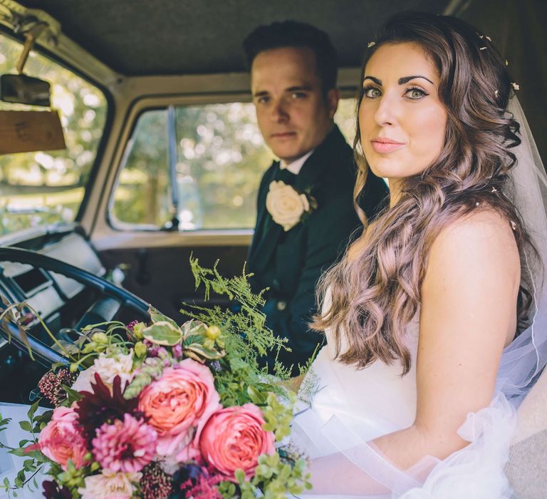 Bride and groom sat in camper van with pink rose bouquet 