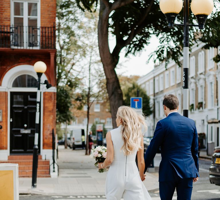 Bride & groom walk together through London as bride wears Alice and Olivia jumpsuit