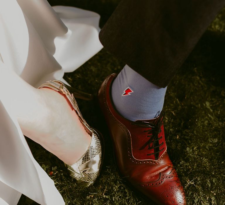 Bride in gold lightning detail open toe heeled sandals and groom in burgundy brogues with lightning motif socks