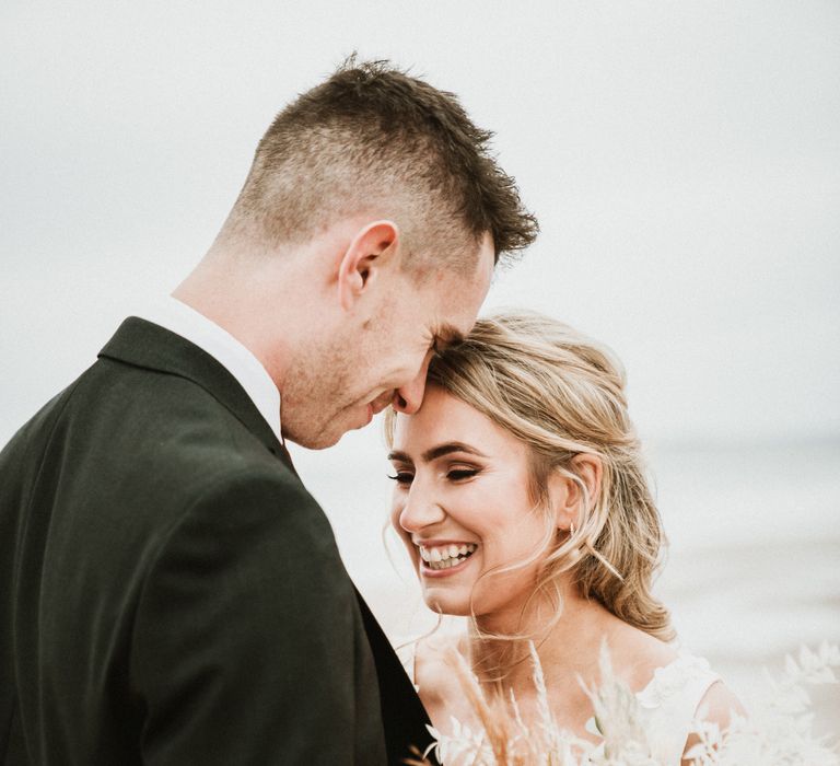 Bride & groom touch foreheads as they stand together on the day of their wedding