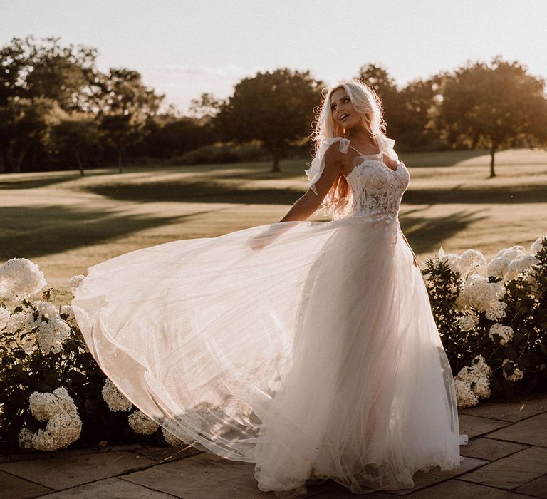 Bride in a princess wedding dress with full skirt and embellished bodice fanning out her dress