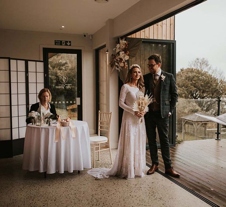 Intimate seaside elopement with ceremony on the terrace. The bride holds a dried flower bouquet 