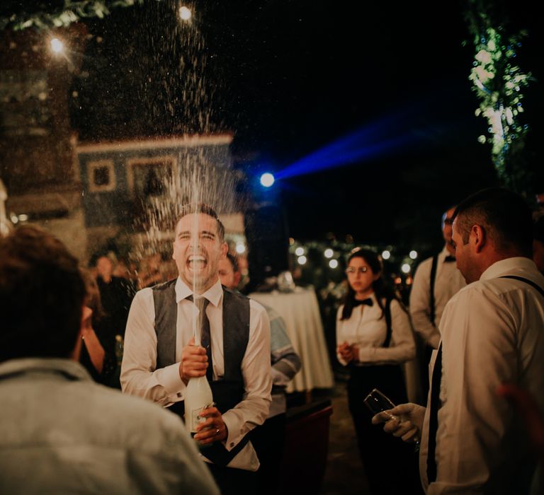 The groom shaking a bottle of champagne in a crowd