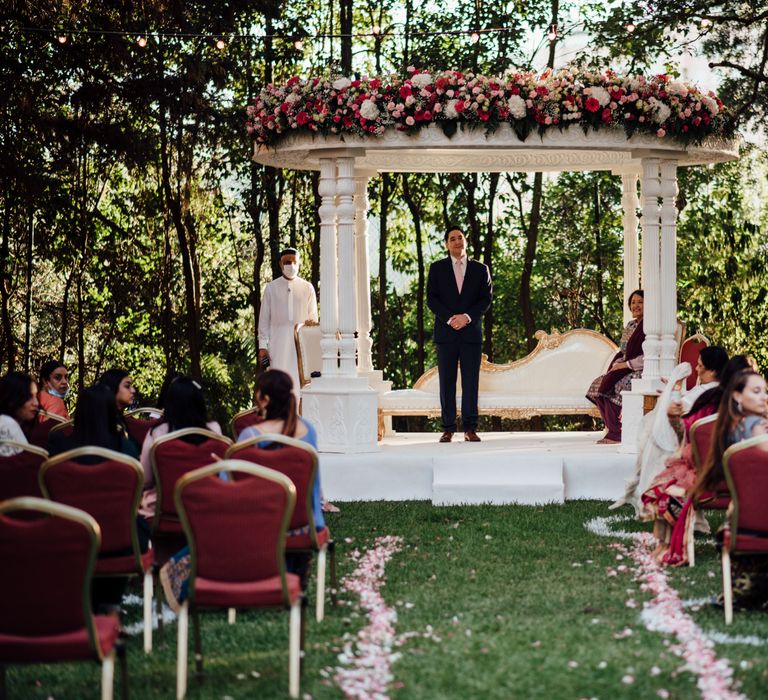 Groom awaits bride at the end of the aisle on their wedding day