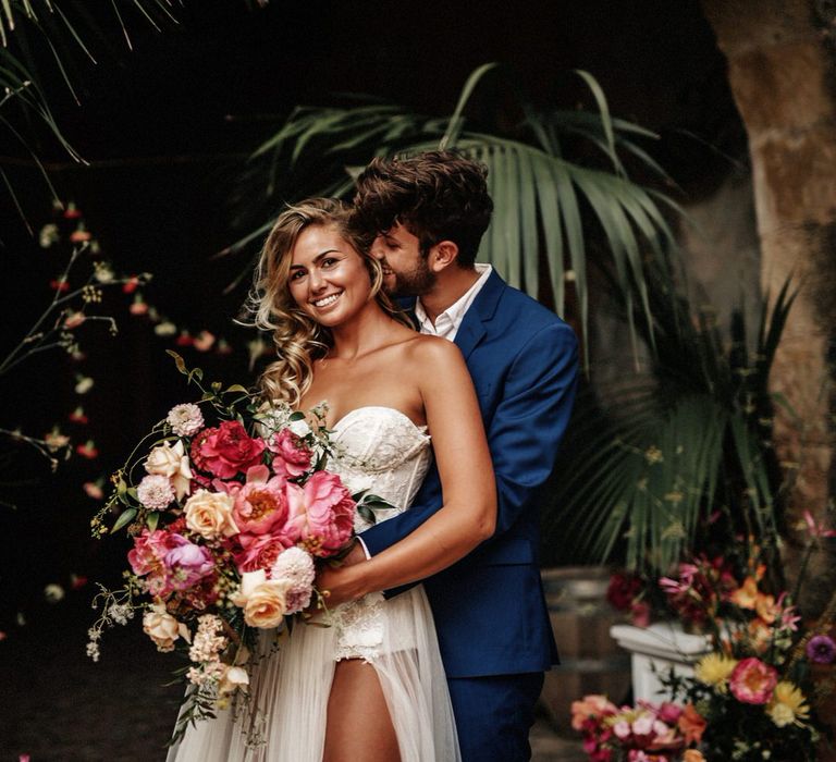 Bride and groom at finca wedding in Spain, surrounded by palm trees and bright pink florals