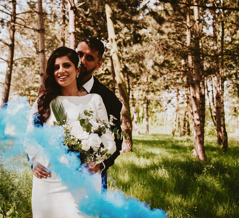 Bride and groom portrait in the woods with a blue smoke bomb