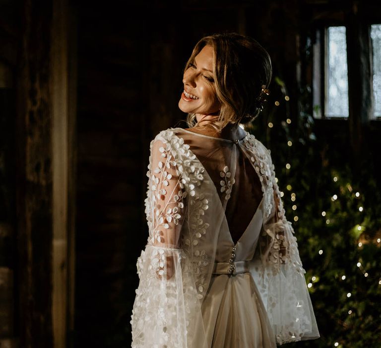 Bride wearing bespoke Delphine Couture wedding dress with embroidered bell sleeve mesh overlay top