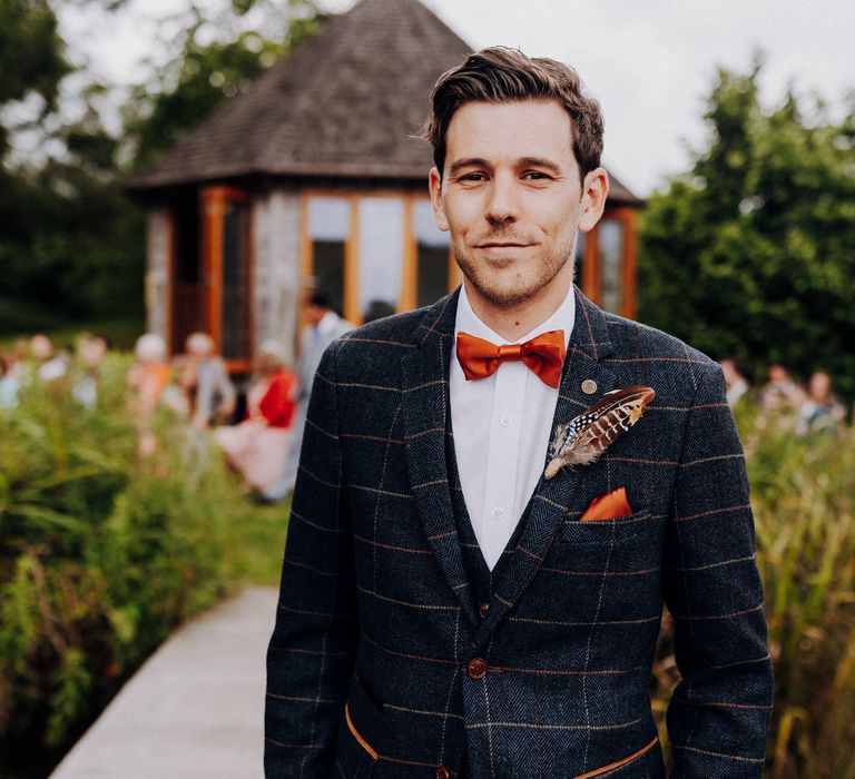 Groom wears Marc Darcy suit with orange thread, pocket square, and orange bow-tie 