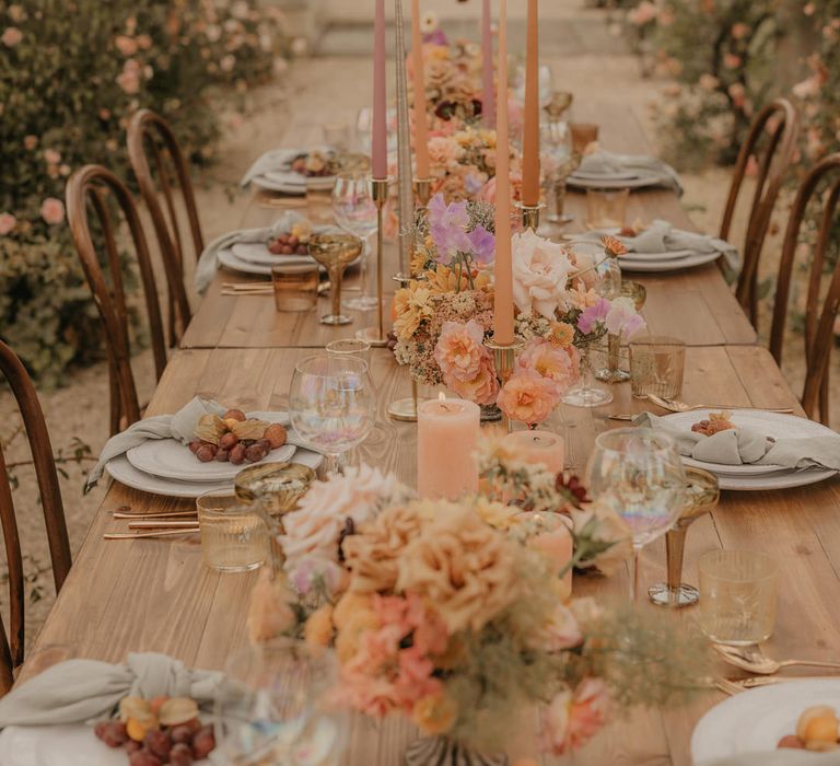 Wedding table decor with flowers, fruits and candles in pastel orange, peach, coral and pink colours 