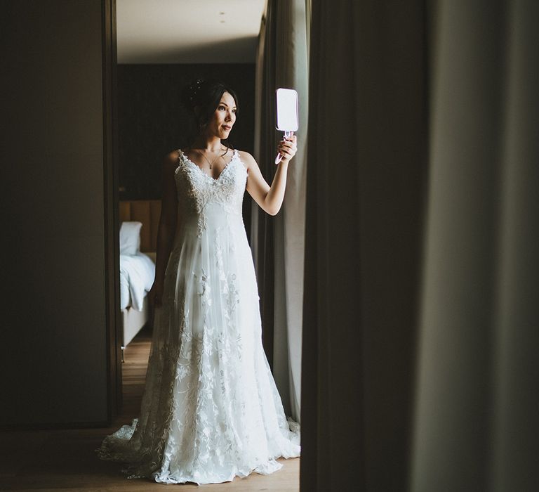 Bride looks at her reflection in hand mirror on her wedding day