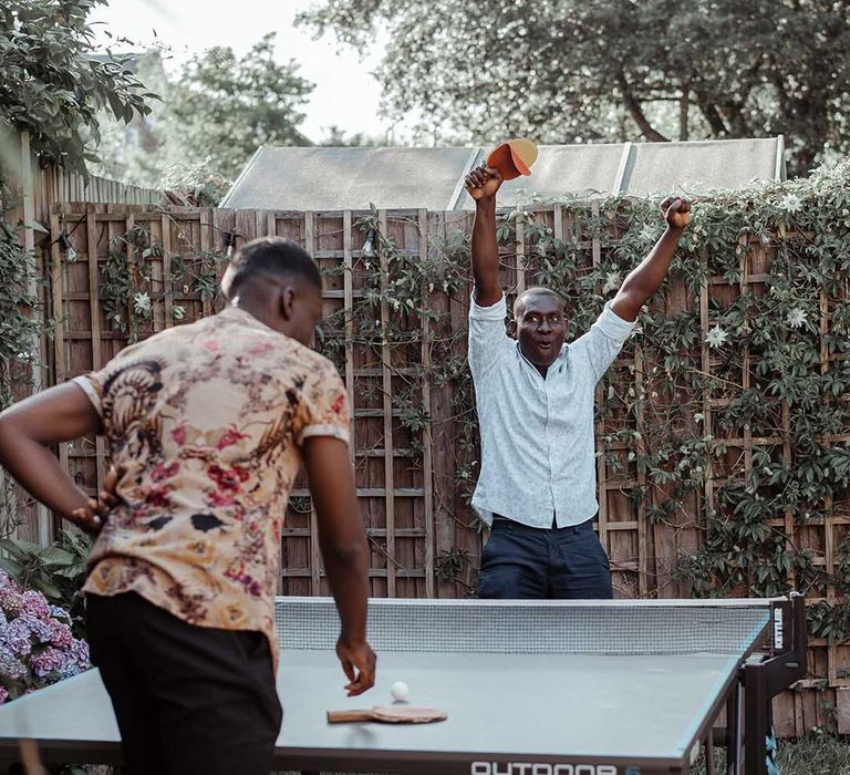 Wedding guests play ping pong outdoors on wedding day