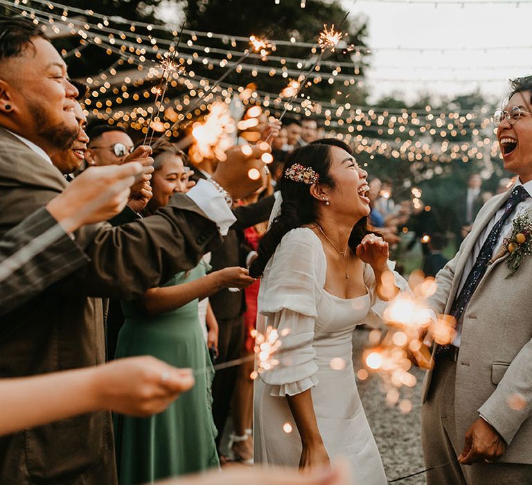 Bride & groom laugh with one another during sparkler exit outdoors on their wedding day