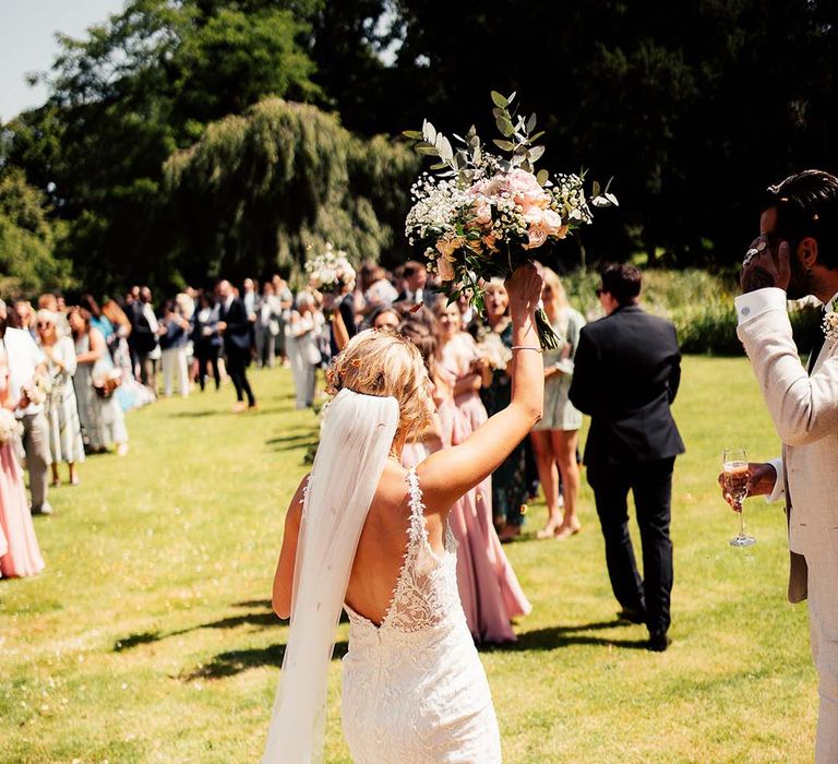 Bride in Made With Love bridal gown with lace detail and blush bouquet