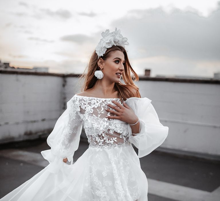 Bride in a short lace wedding dress with long sleeve and long sheer skirt wearing a white appliqué headband 