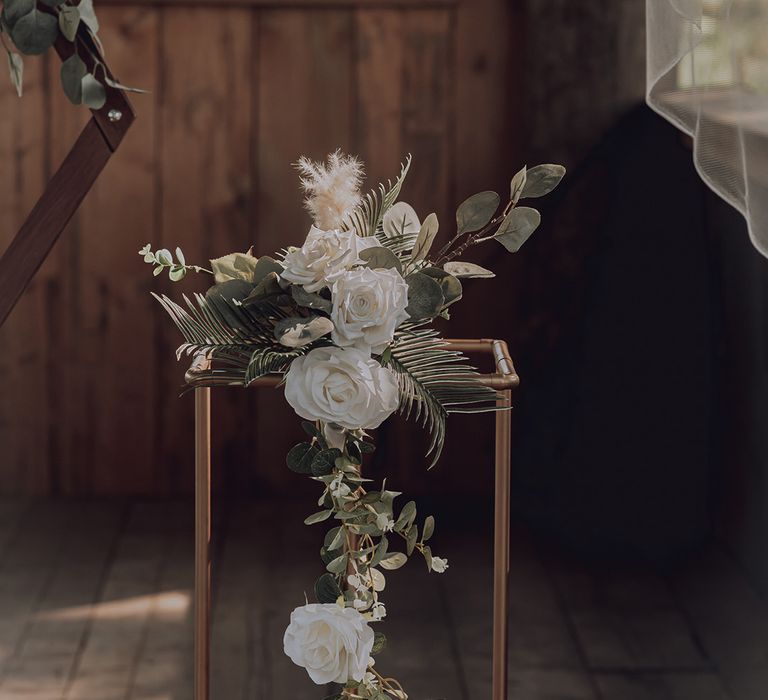 Brass stand complete with white florals and green foliage