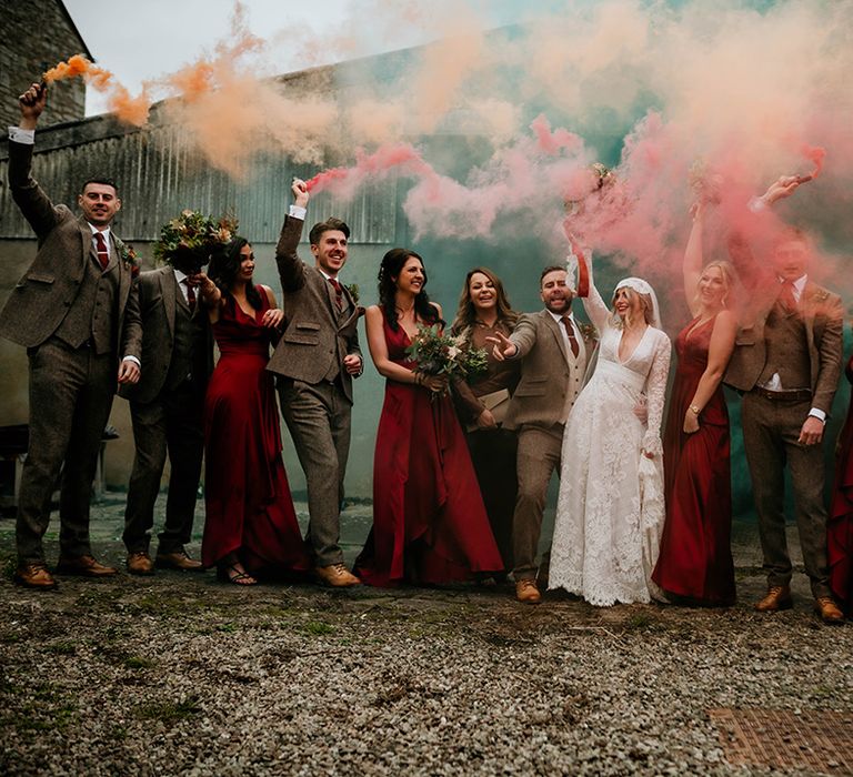 Smoke bomb wedding party portrait at Lyde Court with bride in a lace wedding dress, groomsmen in tweed suits and bridesmaids in satin dresses 