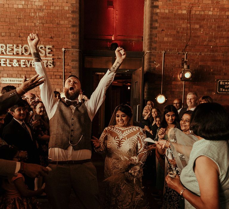 Groom in a tweed waistcoat and pocket watch raising his hand in the after the wedding ceremony 