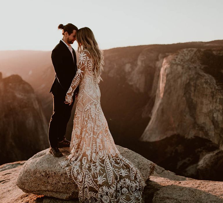 Bride & groom stand on mountain as the sun sets on their wedding day