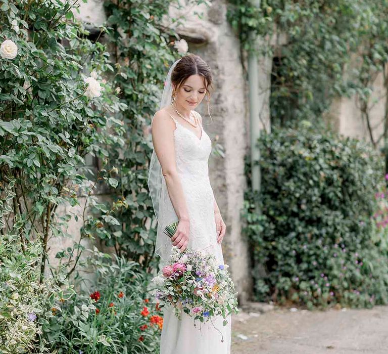 Bride holds pastel bouquet in front of ivory on her wedding day