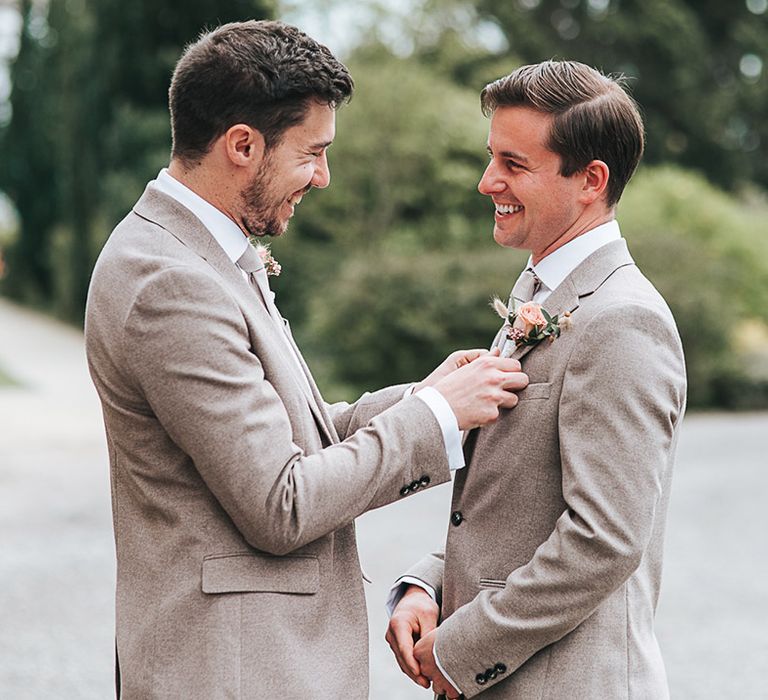 Groomsmen help each other fix their matching outfits 