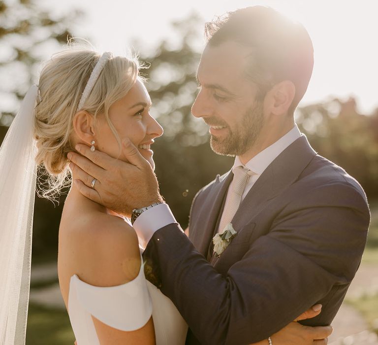 Bride wears her blonde hair pulled back into low loose curled bun with pearl headband and wedding veil 