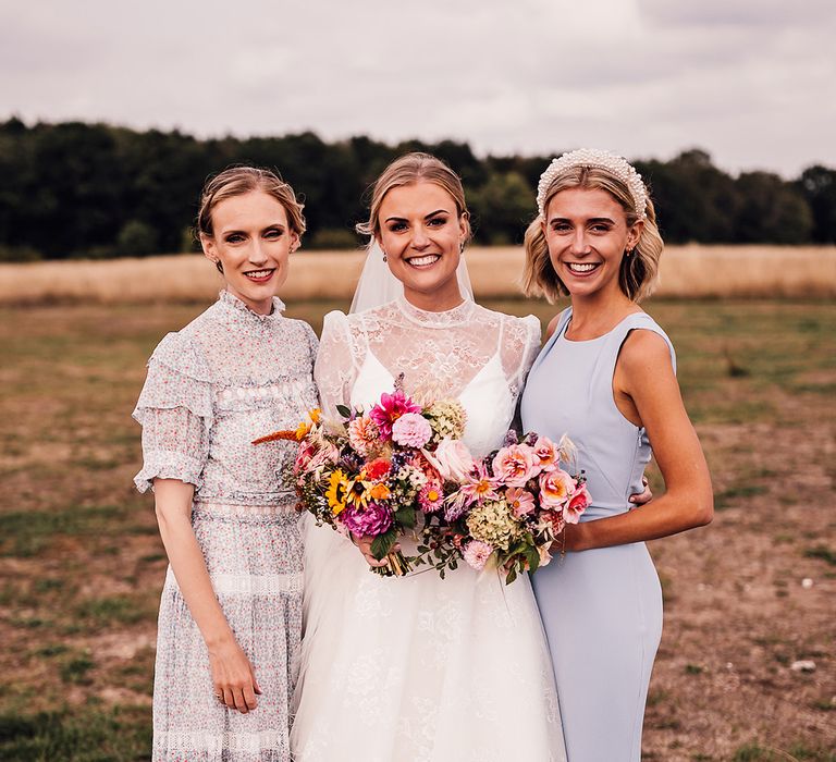 Bride in a long sleeve delicate lace wedding dress with bridesmaid in blue dresses