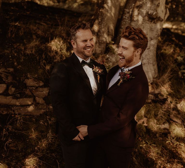 Grooms in black tie laugh together for their couple portraits 