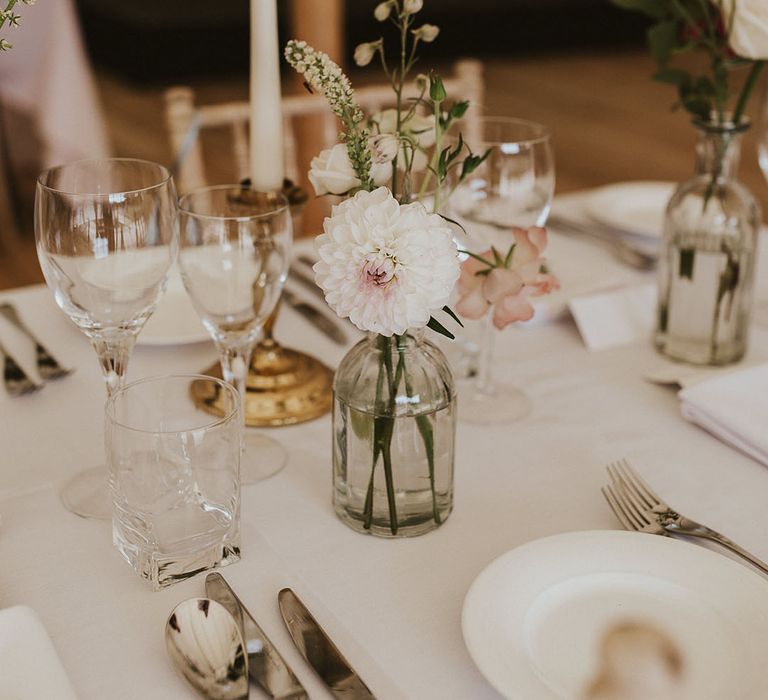 Mini arrangement of pink and white flowers decorating the tables with white taper candles and touches of gold 