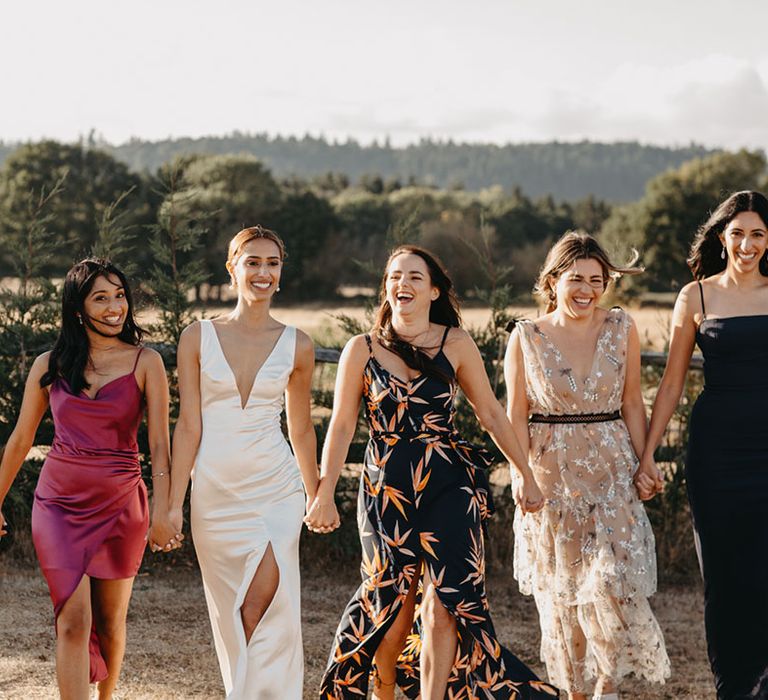 Bride walks with her wedding party in colourful outfits outdoors