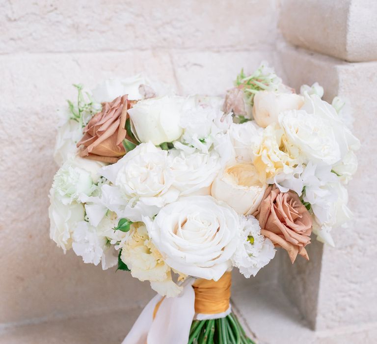 The bridal bouquet for an Italian theme wedding tied with white and gold satin ribbon 