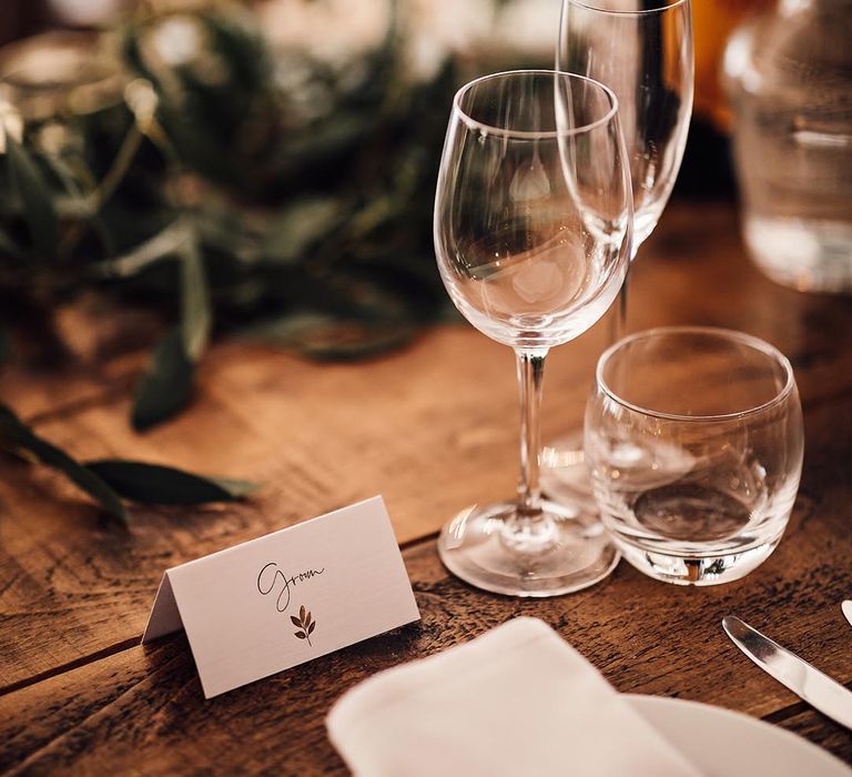 Simple and minimal wedding place name with gold leaf design for classic wooden and white tablescape with foliage 