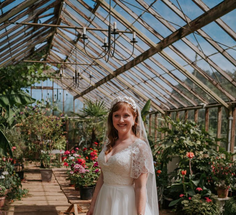 Bride in a lace wedding dress with a large white flower headband and pink and white bouquet 