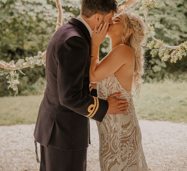 Hula hoop decor for the altar as the bride and groom share their first kiss as a married couple for their boho wedding with a sage green colour scheme