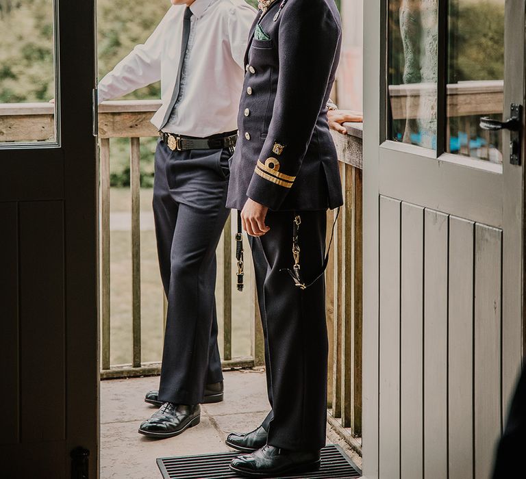 Groom in a double breasted suit jacket with gold accents standing with the groomsmen as they get ready for the wedding 