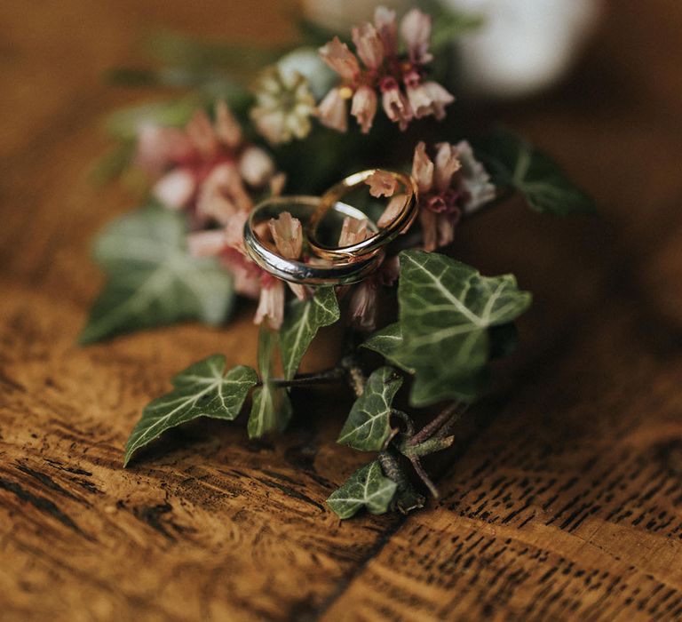 The bride and groom's plain gold wedding bands overlapping on a wedding buttonhole 