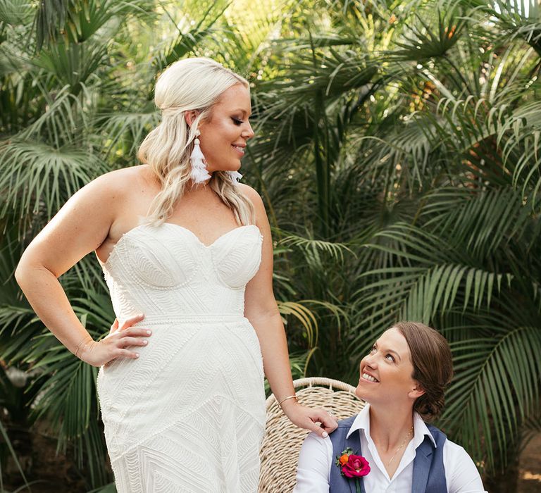 Blonde bride in Rue De Seine wedding dress looks lovingly toward her bride after outdoor wedding in Mexico