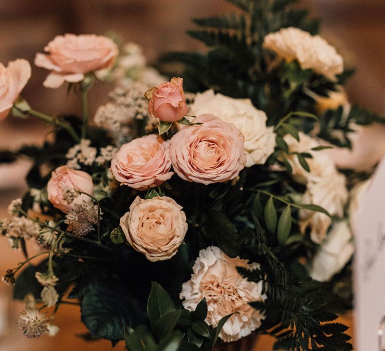 Pink garden roses and white carnation wedding flower arrangement with fern 