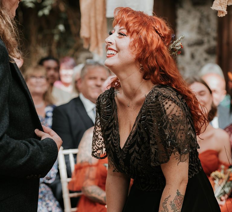 Bride in embellished v-neck black wedding dress laughing and smiling at Devon wedding venue 