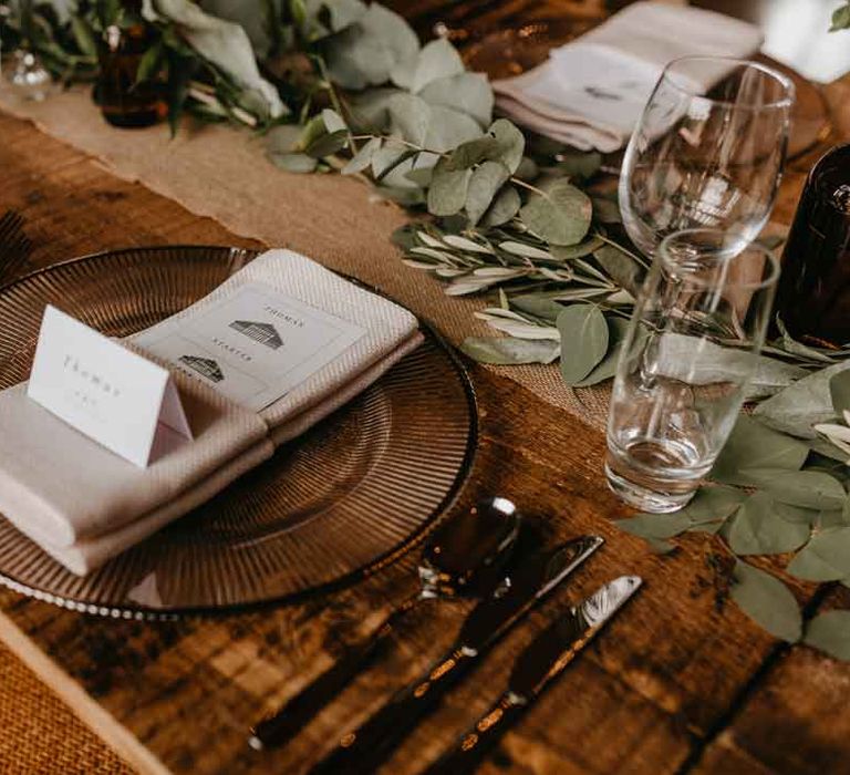 Rustic luxe wedding tablescape with bronze effect plate, linen napkins, minimalistic wedding menu and eucalyptus table runners 