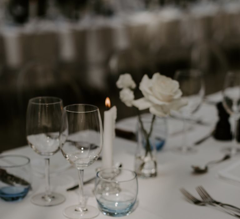 Modern and minimal wedding tablescape with white tablecloth, napkins and menu with silver cutlery and blue ombre glassware 