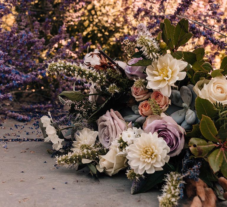 Purple and white wedding bouquet with roses and foliage to match the wedding venue's flowers 