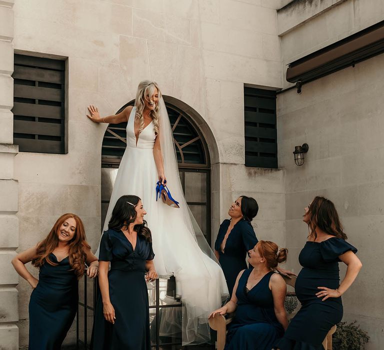 Bridal party in navy mismatched midi bridesmaid dresses with bride in plunging wedding dress 