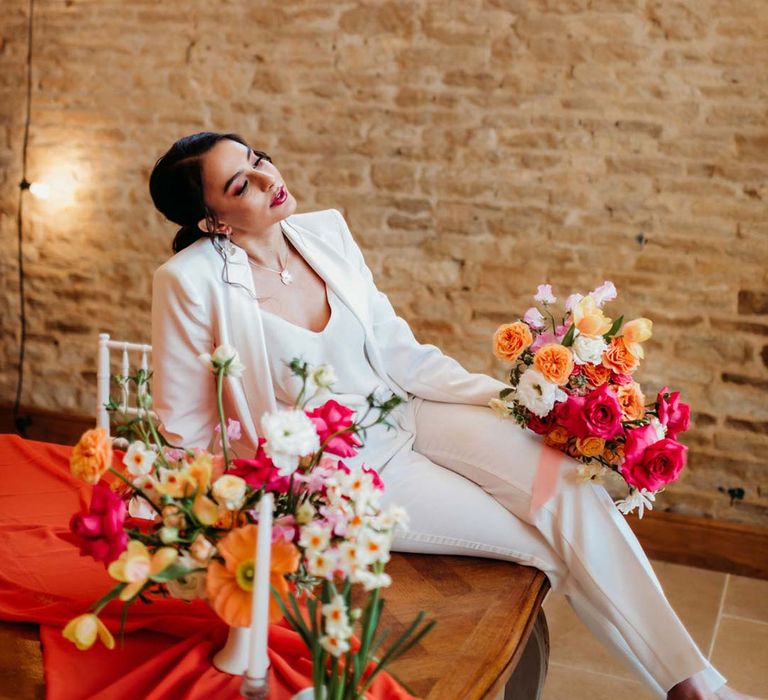 Bride in white bridal suit with closed toe bright green wedding heels holding large mixed flower seasonal bridal bouquet at Merriscourt wedding venue 